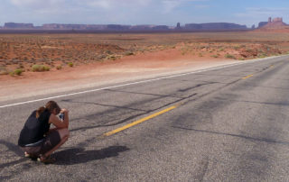 Sabine sitzt auf Straße zum Fotografieren