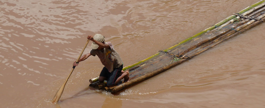 slow-travel-laos Mann auf dem Floß in Laos