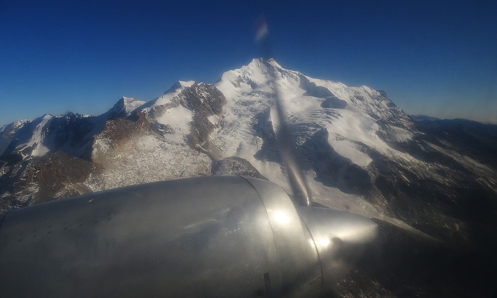 Propellerflugzeug fliegt am Berg entlang