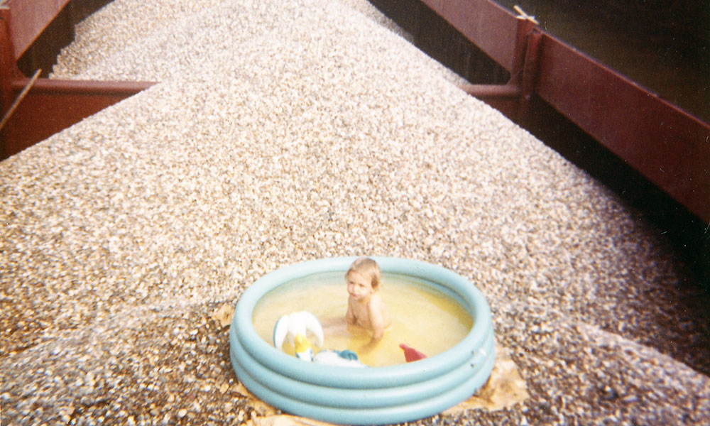 Kleinkind im Swimmingpool auf Kieshaufen