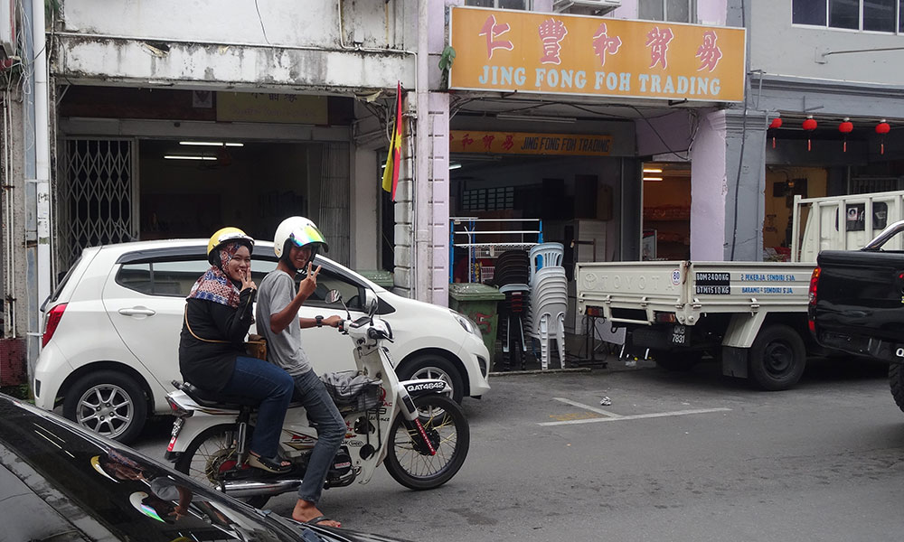 Mann und Frau auf Moped machen das Peace-Zeichen