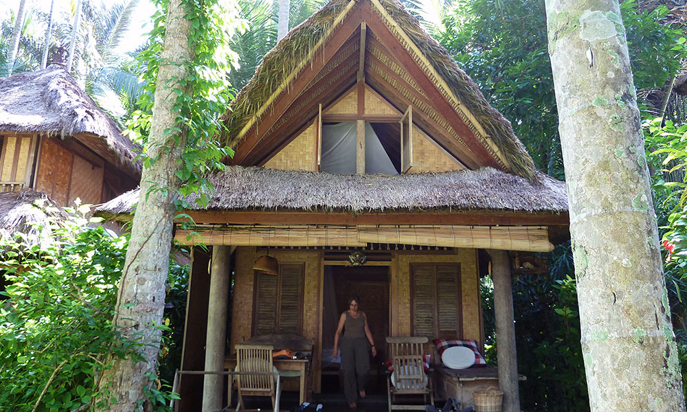 Bambushütte unter Kokospalmen