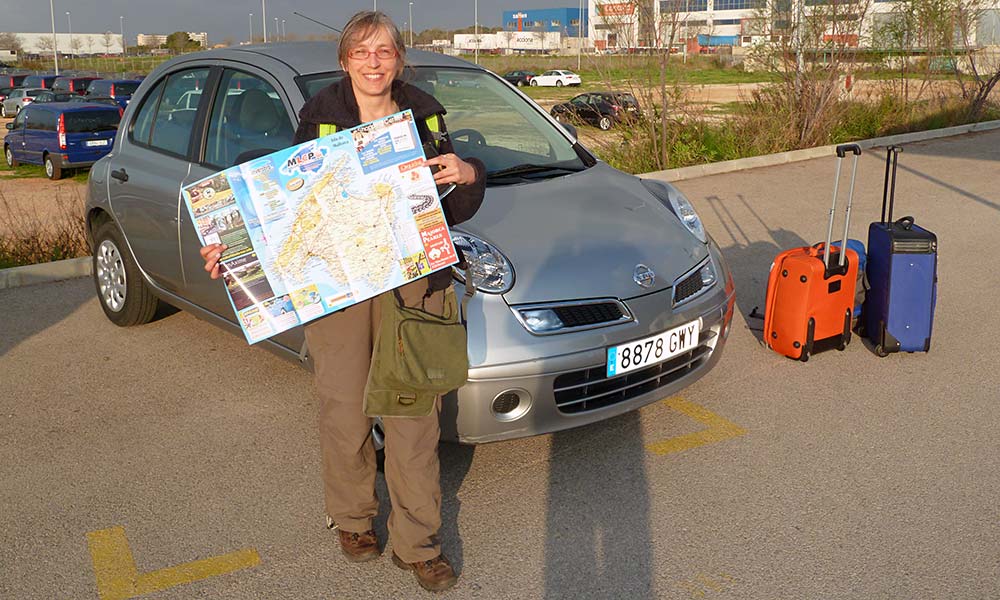 Frau mit Landkarte vor Auto