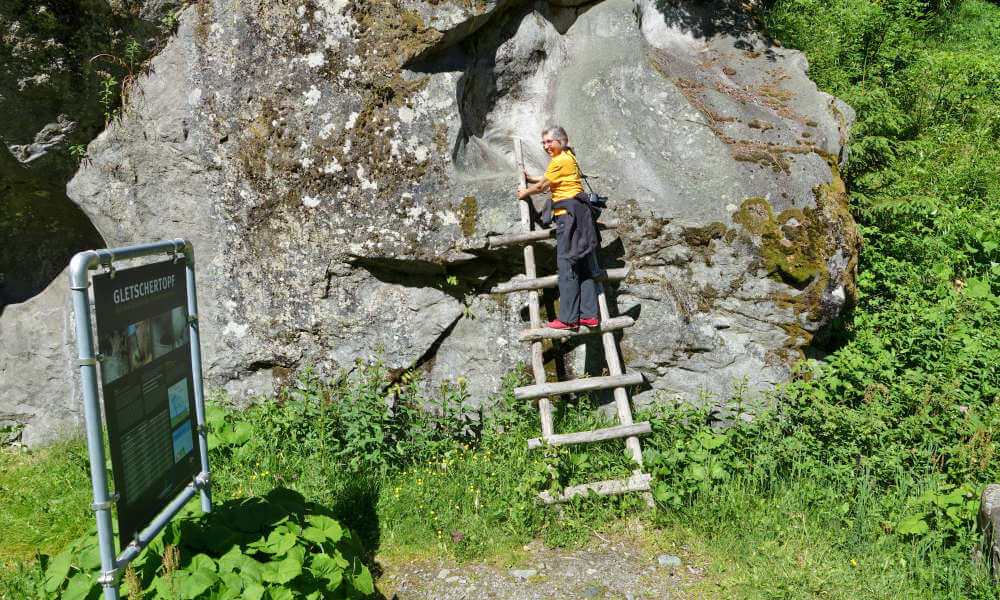 Frau auf Holzleiter an einer Felswand