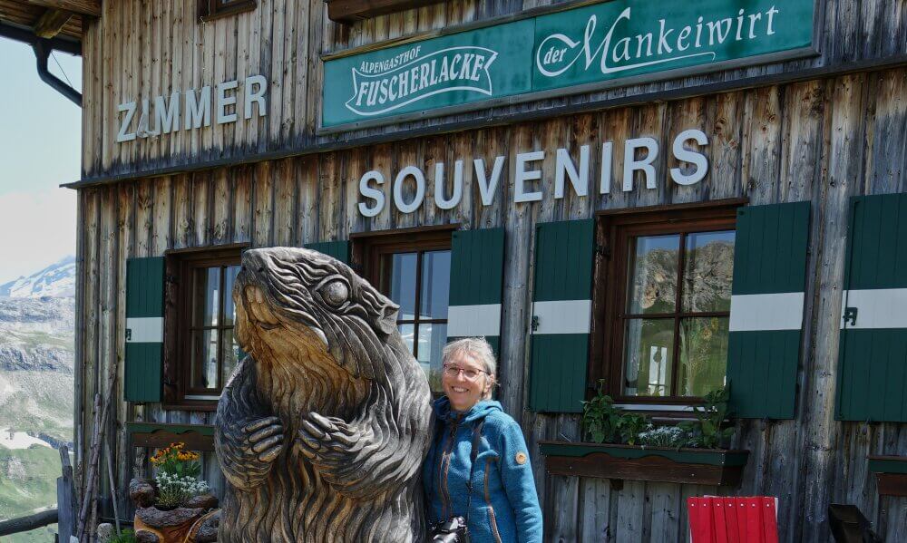 Frau vor Gasthof mit Holzmurmeltier