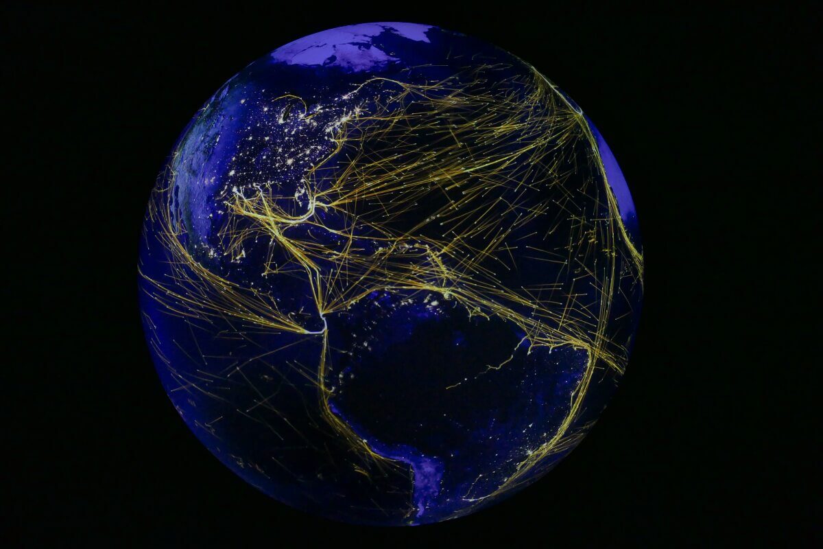 Globus mit gelben Linien von Schiffsrouten auf dem Meer