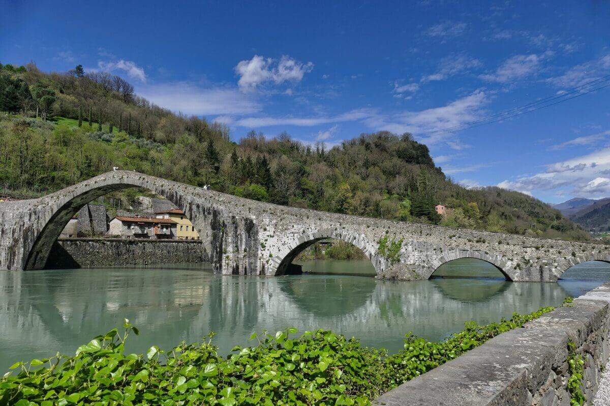 Steinerne Bogenbrücke über grünem Fluss