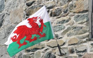 Flagge von Wales mit rotem Drachen weht an einer Hauswand.