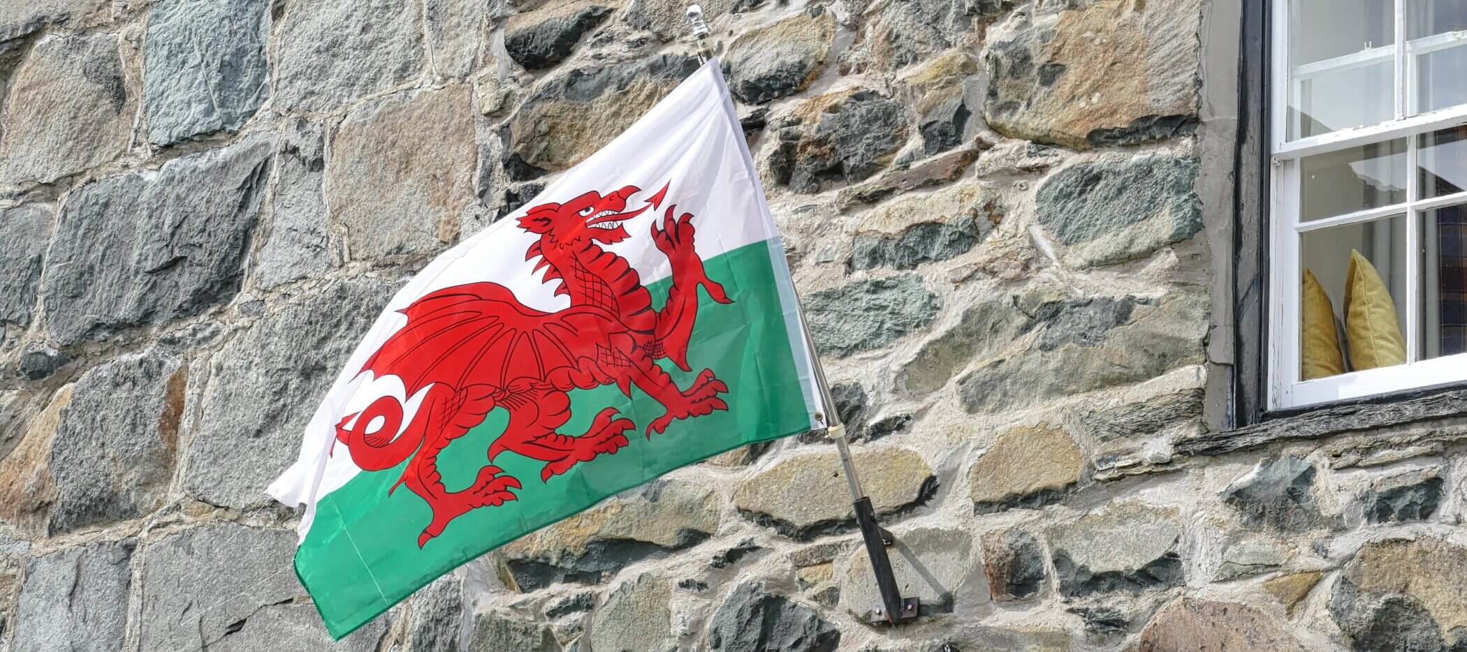 wales-flagge Flagge von Wales mit rotem Drachen weht an einer Hauswand.