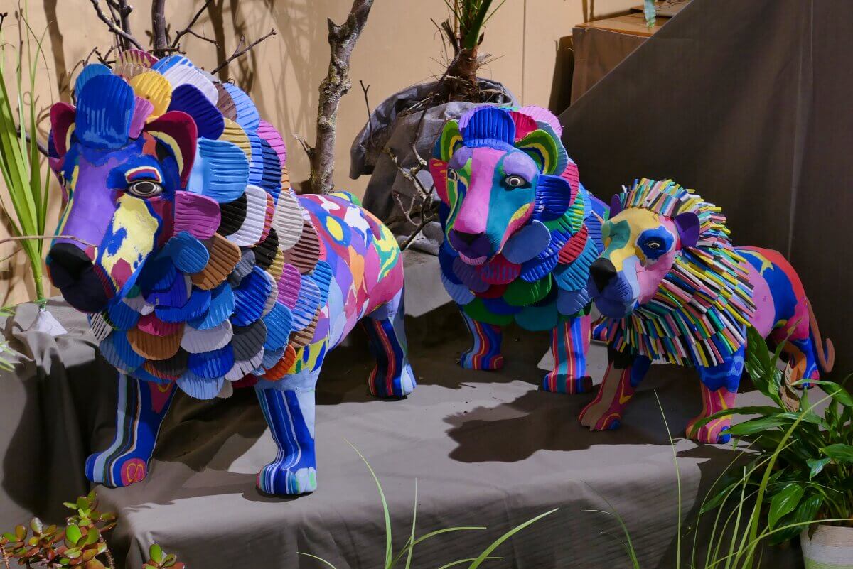 Drei farbenfrohe Tierskulpturen aus alten Flipflops in Blau-, Rosa-, Grün-, Gelb- und Lilatönen. 