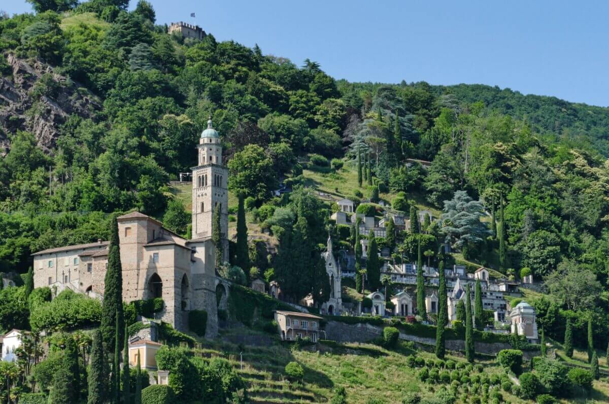 Eine Kirche in den Hügeln zwoschen üppig grünen Bäumen unter einem klaren blauen Himmel. 