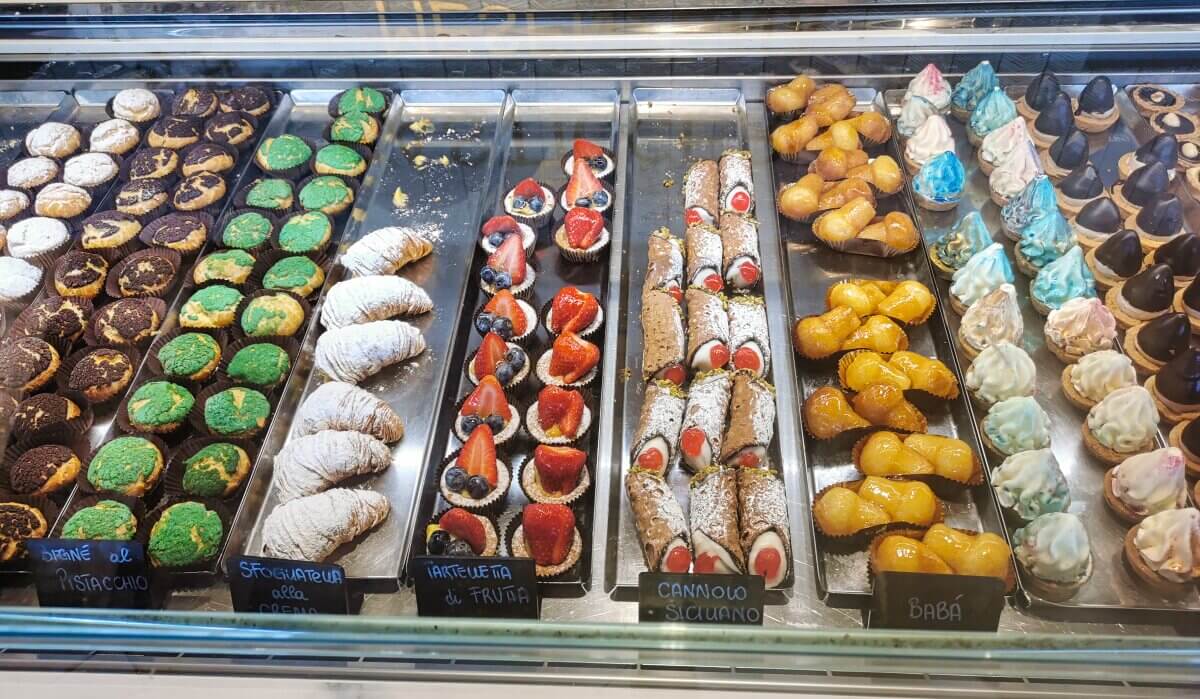 Eine Vitrine mit buntem italienischem Gebäck, darunter Cannoli, Obstkuchen und Meringues. 