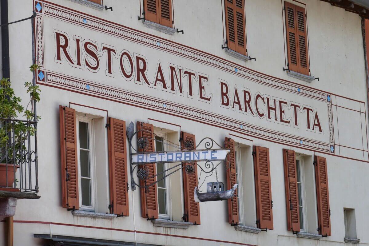 Ein Gebäude mit roten Fensterläden und einem Schild mit der Aufschrift Ristorante Barchetta über den Fenstern. 