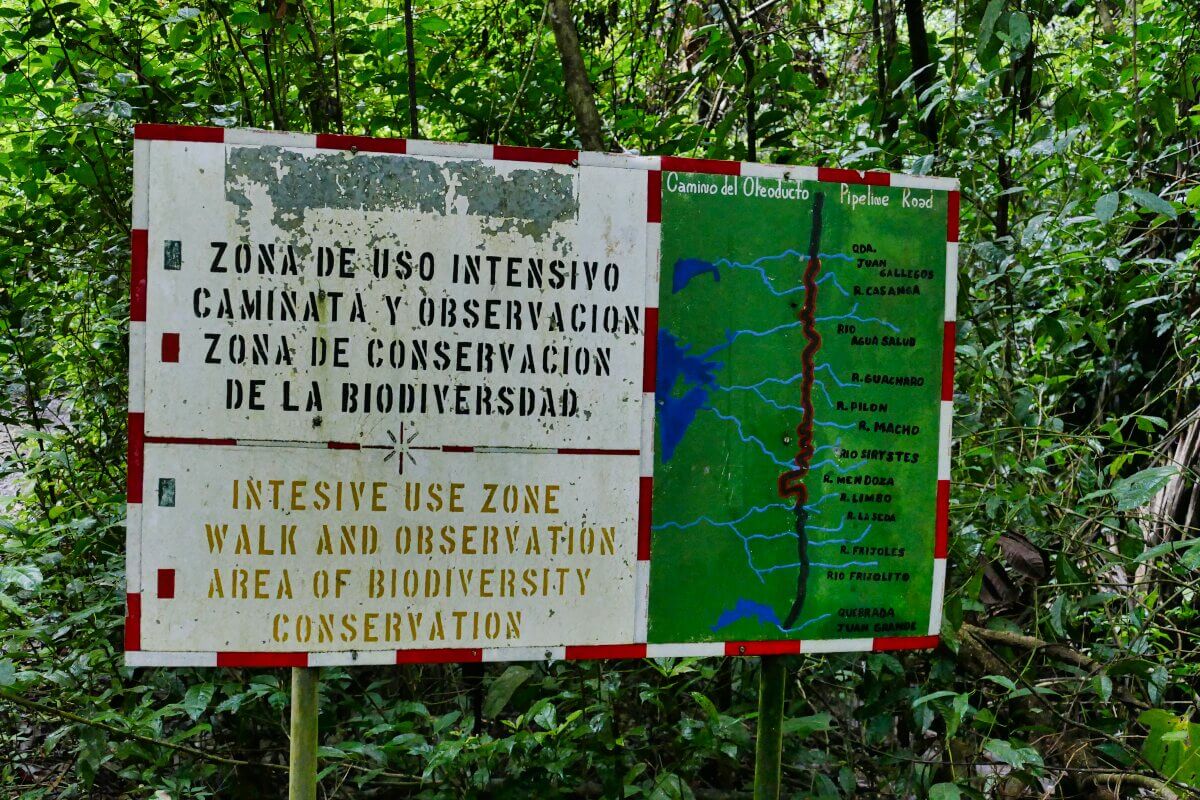 Ein zweisprachiges Schild in einem Wald kennzeichnet eine intensiv genutzte Zone zur Erhaltung und Beobachtung der biologischen Vielfalt.