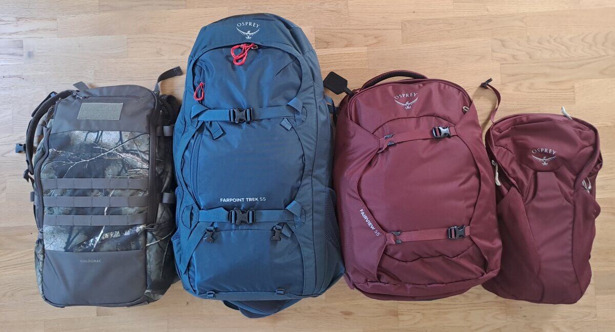 Vier Rucksäcke verschiedener Größen liegen nebeneinander auf dem Fußboden